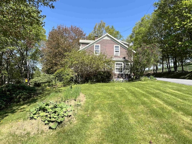 view of side of home featuring a lawn and a chimney