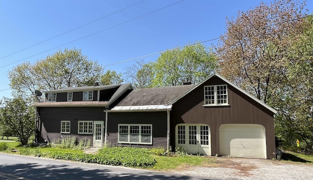view of front of home featuring a garage, a chimney, and driveway