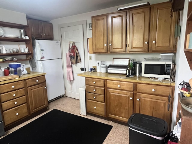 kitchen with white appliances, brown cabinetry, and light countertops