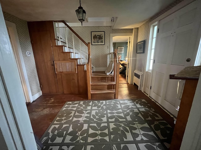 foyer entrance featuring wallpapered walls, radiator heating unit, stairs, and baseboards