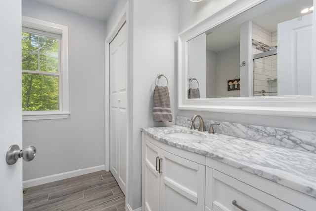 full bath featuring wood finished floors, baseboards, a stall shower, and vanity