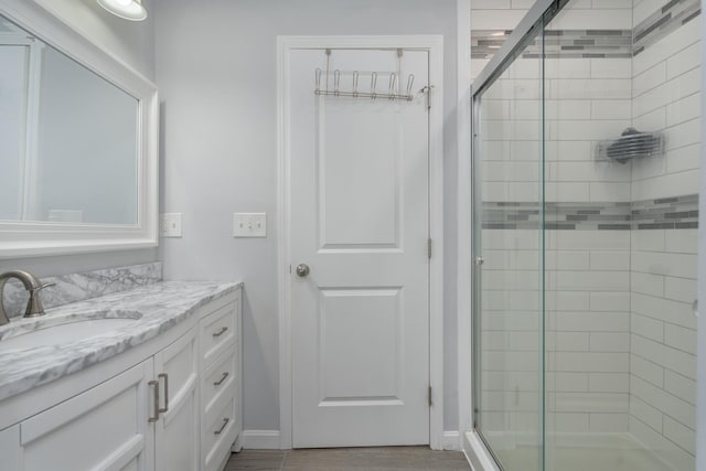 full bath featuring a stall shower, vanity, and baseboards