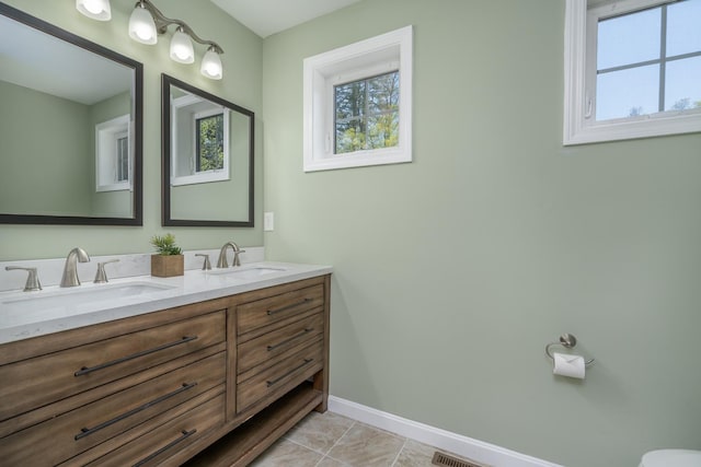 bathroom featuring baseboards and double vanity