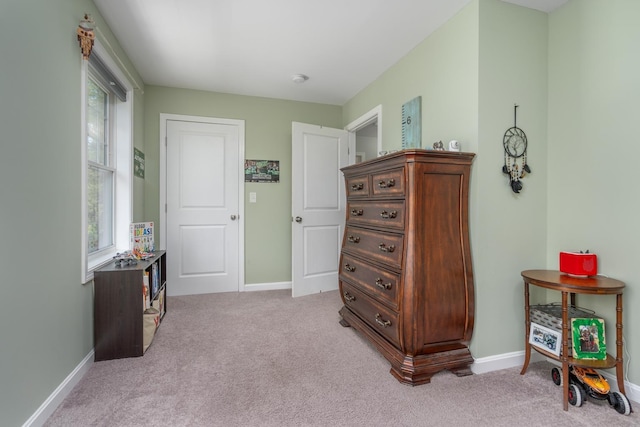 bedroom featuring light colored carpet and baseboards