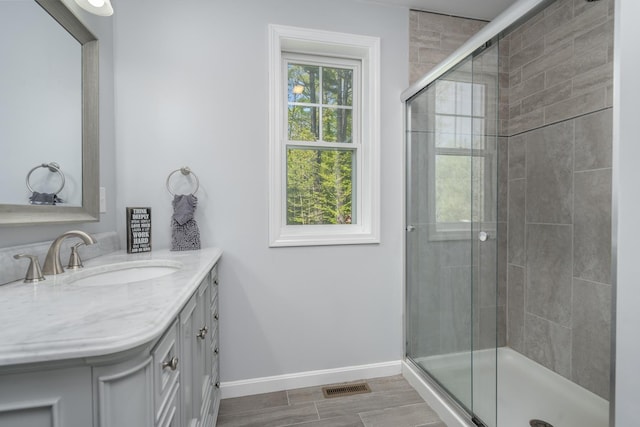bathroom with baseboards, a shower stall, and vanity