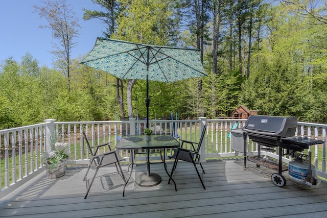 deck with outdoor dining area, area for grilling, and a playground