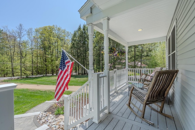 wooden terrace featuring covered porch and a yard