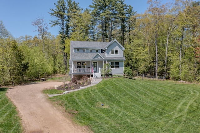 view of front facade featuring a porch, dirt driveway, a front yard, and a view of trees