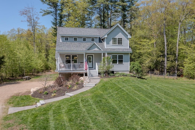 traditional-style house featuring covered porch, a shingled roof, and a front yard