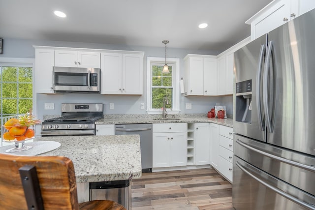kitchen with stainless steel appliances, a sink, white cabinets, recessed lighting, and wood finished floors