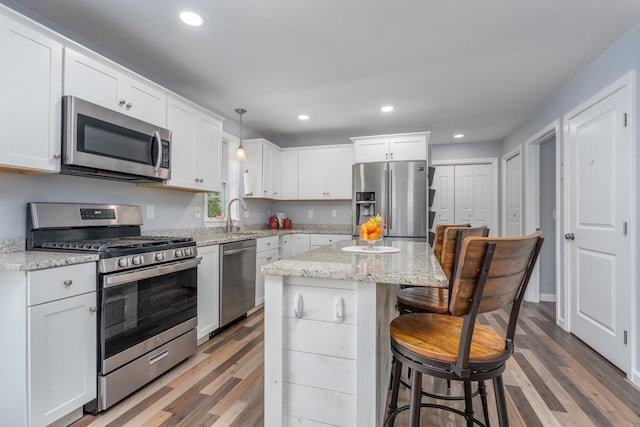 kitchen featuring appliances with stainless steel finishes, light wood-style flooring, recessed lighting, a kitchen breakfast bar, and a center island