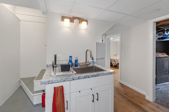 74 Pine St, Rollinsford, NH 03869 - kitchen featuring a sink, white cabinets, light wood-type flooring, baseboards, and a paneled ceiling