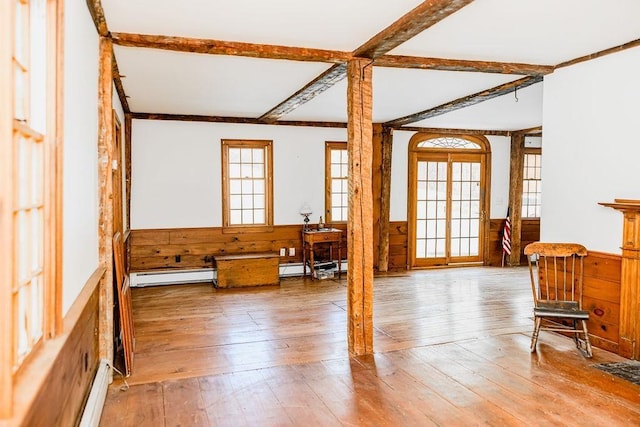 unfurnished room with a baseboard heating unit, wainscoting, hardwood / wood-style floors, and wood walls
