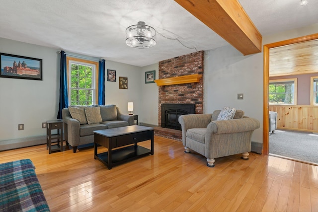 living area featuring light wood-type flooring, plenty of natural light, a fireplace, and a chandelier
