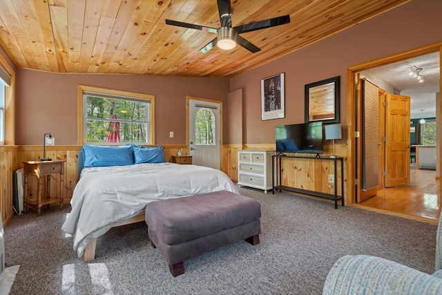 bedroom featuring a wainscoted wall, wood ceiling, vaulted ceiling, carpet, and ceiling fan