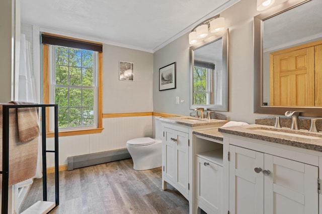 bathroom with wood finished floors, plenty of natural light, wainscoting, toilet, and crown molding