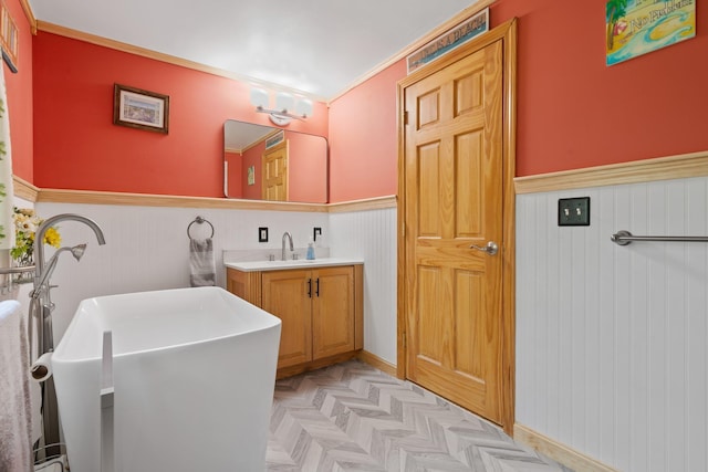 bathroom featuring a wainscoted wall, a soaking tub, and vanity