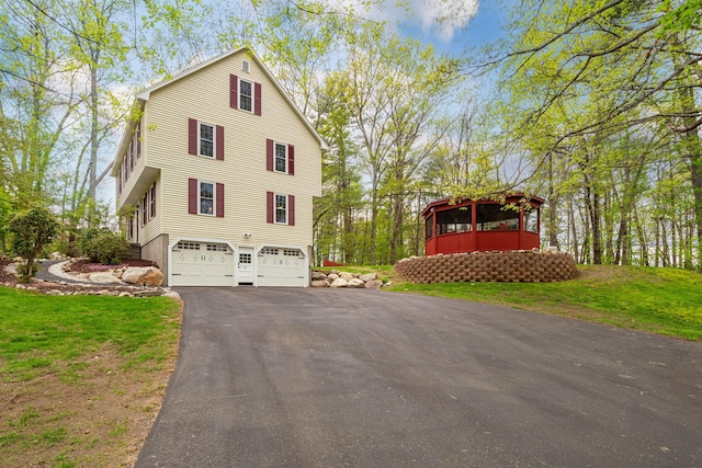 view of property exterior featuring a garage, asphalt driveway, and a yard