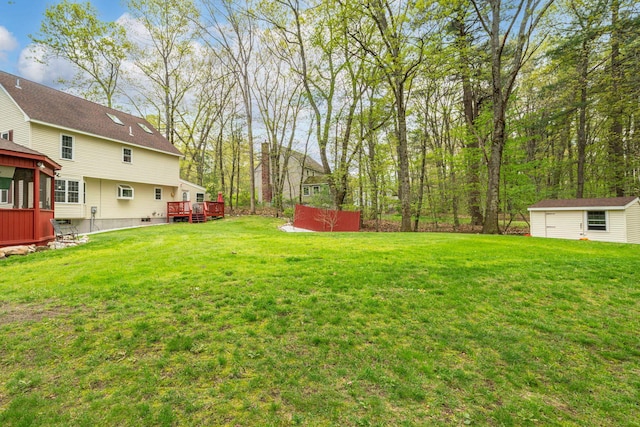 view of green lawn with a wooden deck and an outbuilding