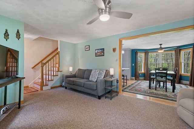 carpeted living area with ceiling fan, stairs, and baseboards