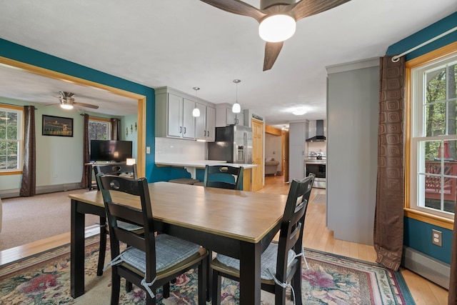 dining space featuring a ceiling fan, baseboards, plenty of natural light, and light wood-type flooring