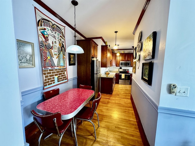 98 Pennacook St, Manchester, NH 03102 - kitchen with stainless steel appliances, light wood-style floors, decorative light fixtures, ornamental molding, and a kitchen island