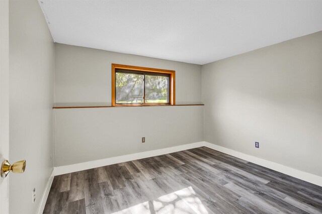 empty room featuring wood finished floors and baseboards