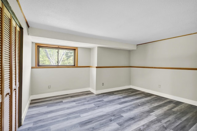 basement featuring wood finished floors, a textured ceiling, and baseboards