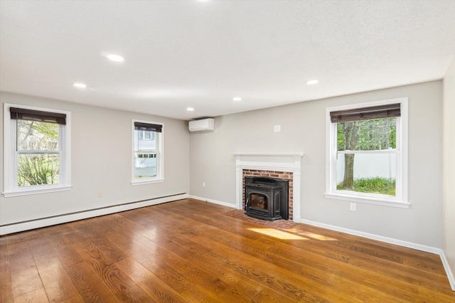 unfurnished living room featuring a wall mounted air conditioner, a wood stove, a baseboard radiator, plenty of natural light, and recessed lighting