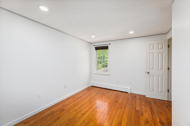unfurnished room with a baseboard heating unit, baseboards, light wood-style flooring, and recessed lighting