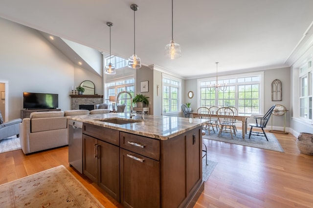 kitchen featuring a sink, light wood-style floors, dishwasher, a stone fireplace, and ornamental molding