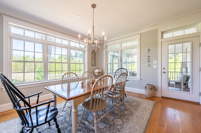 dining room featuring a chandelier, light wood-type flooring, baseboards, and ornamental molding