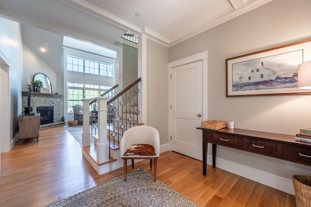 foyer featuring light wood-type flooring, stairway, crown molding, a fireplace, and baseboards