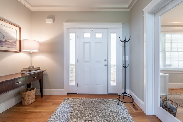 foyer with light wood-style floors, ornamental molding, and baseboards