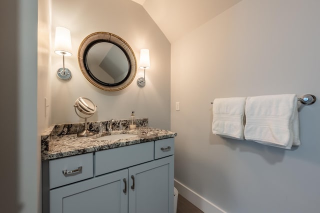 bathroom featuring lofted ceiling, vanity, and baseboards
