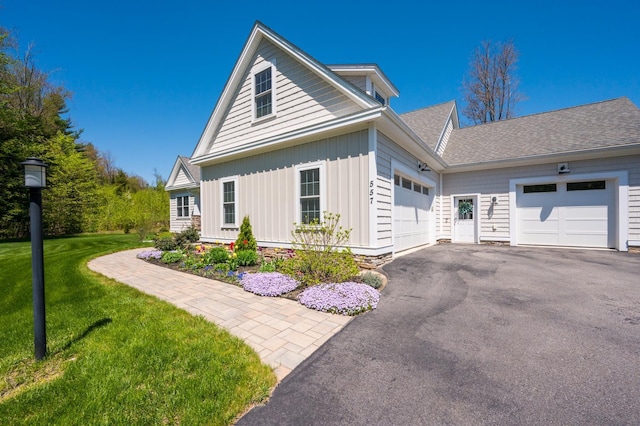 view of front facade with a garage, board and batten siding, a front lawn, asphalt driveway, and roof with shingles