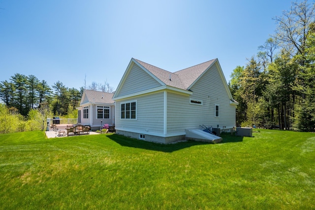rear view of property with a yard, a shingled roof, and central AC