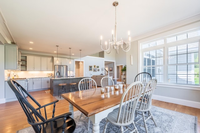 dining space featuring a chandelier, light wood-type flooring, baseboards, and recessed lighting