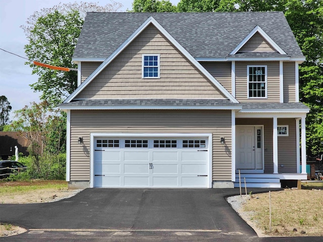 view of front of house featuring driveway, a garage, a shingled roof, and a porch