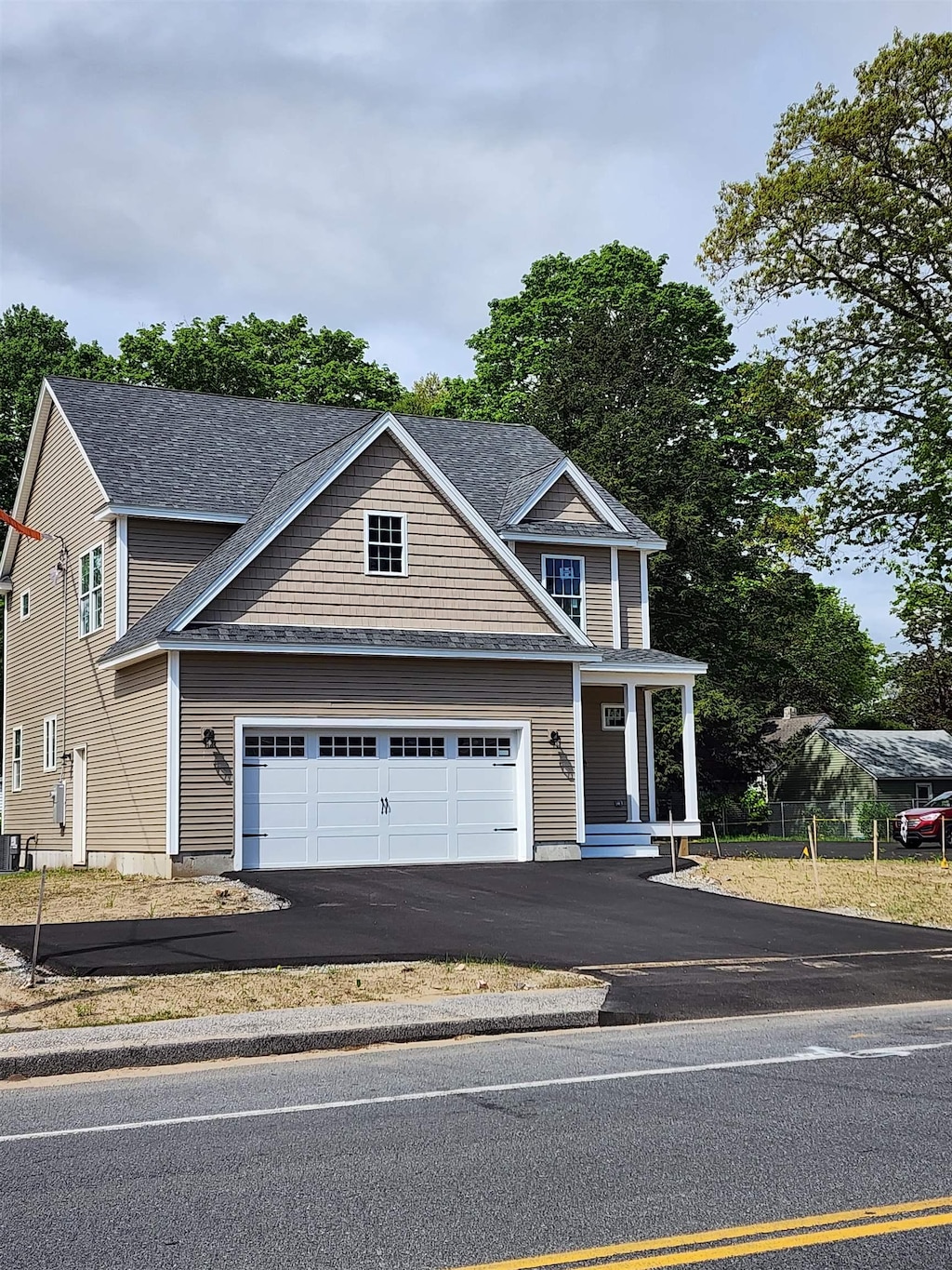 view of front of property featuring asphalt driveway, an attached garage, and a shingled roof