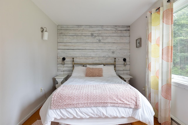 67 Birch Tree Ln, Fayston, VT 05673 - bedroom with baseboard heating, an accent wall, baseboards, wood finished floors, and wooden walls