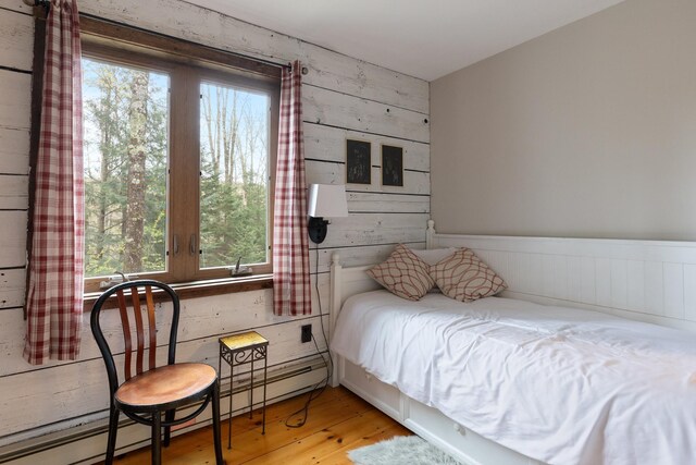67 Birch Tree Ln, Fayston, VT 05673 - bedroom featuring a baseboard radiator, multiple windows, light wood-type flooring, wooden walls, and a wainscoted wall