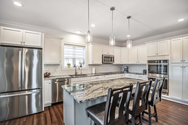 20 Del Ray Dr, Windham, NH 03087 - kitchen with stainless steel appliances, a sink, white cabinets, a kitchen breakfast bar, and decorative backsplash