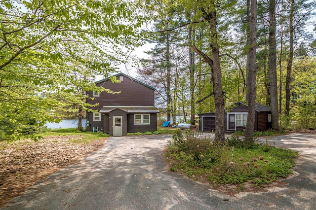 59 Lake Rd, Wakefield, NH 03872 - view of front of house featuring asphalt driveway, an outbuilding, and a water view
