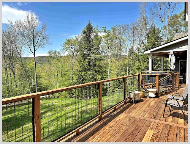 wooden deck with a lawn and a view of trees