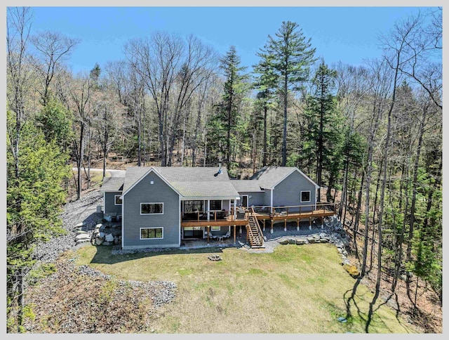 rear view of house with a deck, a lawn, stairway, and a wooded view