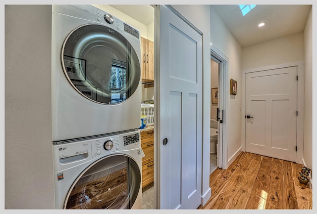 washroom featuring stacked washing machine and dryer, light wood-style floors, a skylight, and recessed lighting