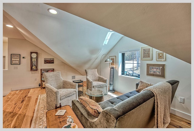 living room featuring vaulted ceiling, wood finished floors, baseboards, recessed lighting, and a skylight