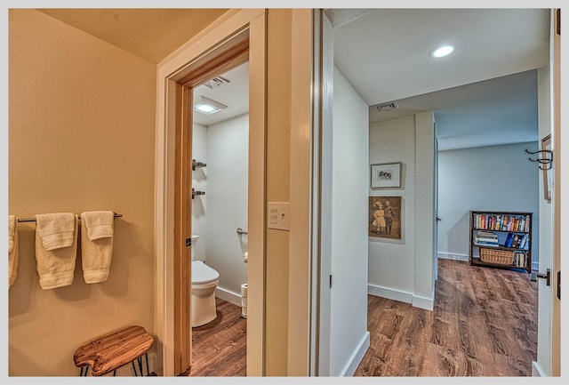 bathroom with wood finished floors, toilet, and baseboards