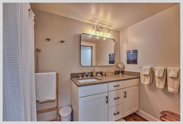 bathroom with vanity, wood finished floors, baseboards, and curtained shower